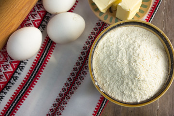 Cooking wooden utensils and flour, eggs, butter on wooden kitchen table. Food cooking template concept. Top view with copy space. Flat lay