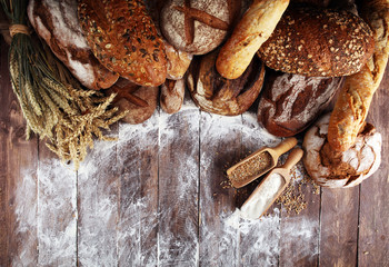 Different kinds of bread and bread rolls on board from above. Kitchen or bakery