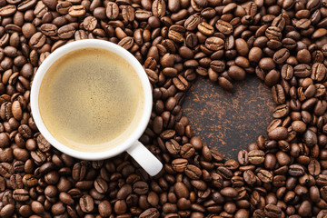 Coffee cup on roasted coffee beans and heart shaped frame.