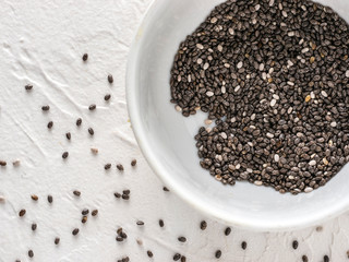 Fototapeta na wymiar Chia seeds with copy space. Chia seed on white concrete textured background. Top view or flat lay. Copy space. Healthy food and diet concept