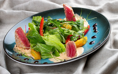 Salad with orange and tuna on textile background