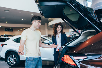 selective focus of smiling car dealer and happy customer standing near new car