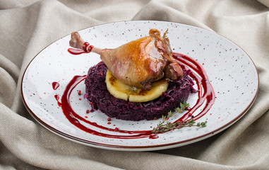 Duck leg with apple and cabbage on textile background