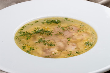 Chicken soup on a white plate on a textile background
