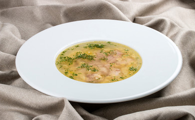 Chicken soup on a white plate on a textile background