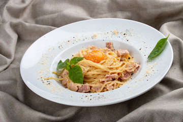Spaghetti Carbonara on white plate on textile background