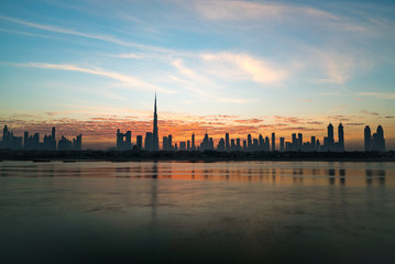Fototapeta premium Morning or sunrise in Dubai. Dawn over Burj Khalifa. Beautiful colored cloudy sky over downtown Dubai. Glow over buildings