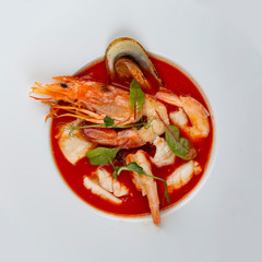 French bouillabaisse fish soup with shrimp, mussels and scallop. In a white plate on a textile background. Top view