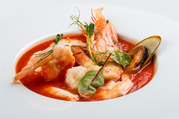 French bouillabaisse fish soup with shrimp, mussels and scallop. In a white plate on a textile...