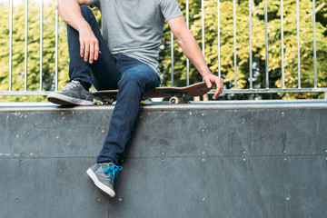 Skateboarding guy. Leisure and lifestyle. Rest and relaxation. Man sitting on skateboard. Copy space.