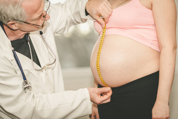 Doctor measuring belly size of pregnant woman