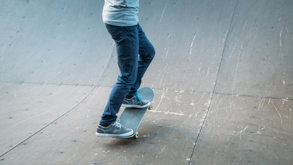Obraz na płótnie Canvas Urban skater in action. Practice time. Man riding skateboard. Legs in jeans. Cropped shot. Skate park ramp. Copy space.
