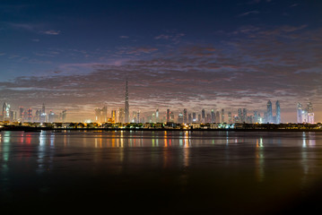 Night or dusk in Dubai. Dawn over Burj Khalifa. Nightly Dubai downtown. View from sea to Dubai quay