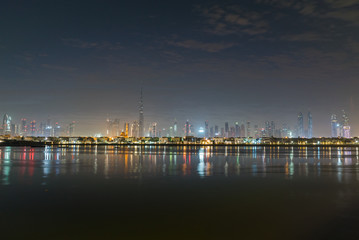 Fototapeta na wymiar Dubai in night city lights or dusk. Dawn over Burj Khalifa. Nightly Dubai downtown. View from sea to Dubai quay