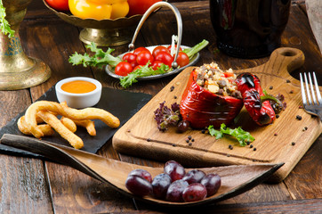Grilled red bell pepper stuffed with meat and rice, served fresh lettuce on a light wooden board....