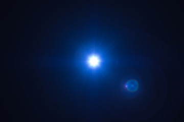 Blue flash spark on black background. Lens flare effect. Defocused spotlight glow