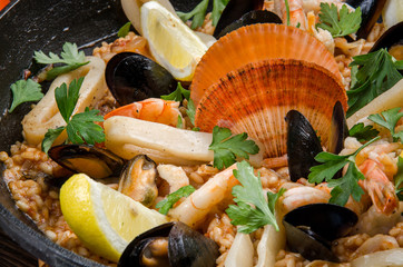 Traditional Spanish dish - Paella with seafood: shrimps, squids, mussels; wine, lemon and rice in a...