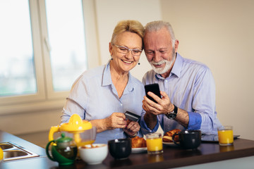 Fototapeta na wymiar Modern senior couple shopping online with phone and credit card