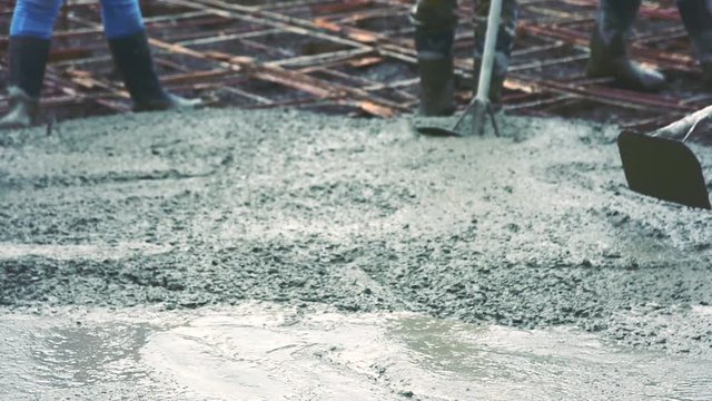 People plastering cement skimming the concrete surface from Pouring ready-mixed concrete on steel reinforcement to make the road by mixing mobile the concrete mixer.