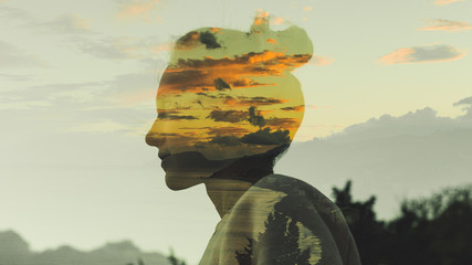 warm profile double exposure portrait of young woman with hair bun during dusk