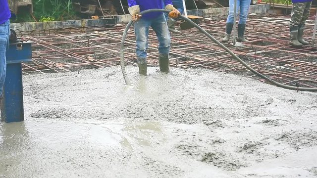 Workers man using a Vibration Machine for eliminate bubbles in concrete. after Pouring ready-mixed concrete on steel reinforcement to make the road by mixing mobile the concrete mixer.