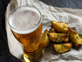 A glass of cold light beer on a wooden table and fries by country