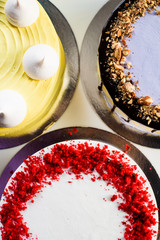 Assorted cakes: red velvet, purple nut cake and yellow cake decorated with meringue close up.  top view. flat lay