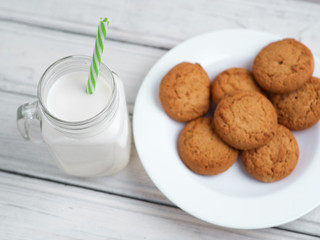 Milk and cookies on a wooden white table
