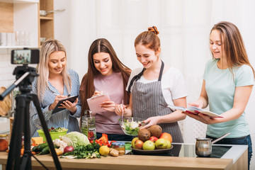 Cooking class. Healthy nutrition. Group of young females writing recipe. Smartphone video shooting.