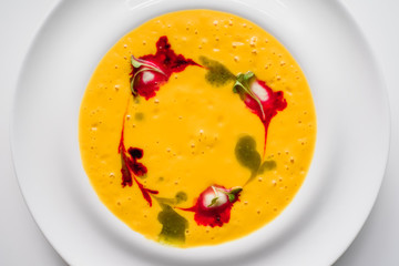 beautifully decorated pumpkin cream soup in a white plate isolated on a white background. top view. flat lay. close-up. light background. space. 