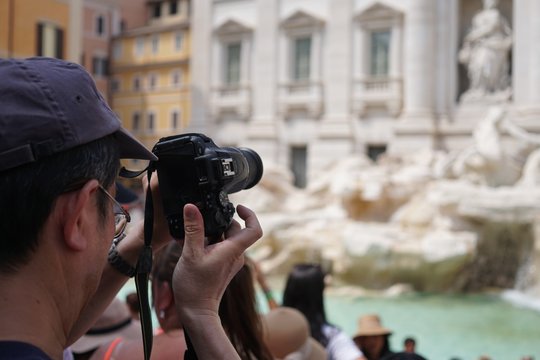 Back turned tourist taking a photo in Rome Trevi Fountain