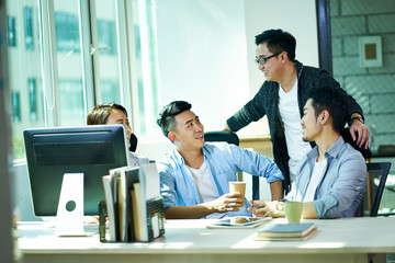 four young asian business people chatting in office
