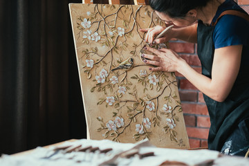 Artwork in process. Inspiration. Woman artist with tool creating. Canvas on easel. Flowers and...