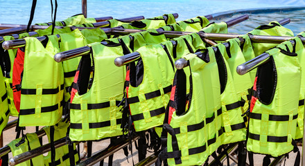 Group of green Life jacket on a steel rail beside the pool.Concept background.
