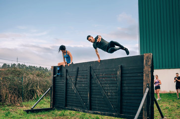 Group of participants in an obstacle course climbing a wall