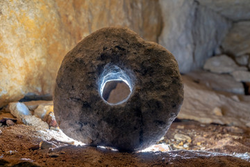 stone wheel in a cave illuminated by counter light