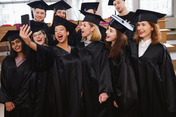 Multi ethnic group of graduated students taking selfie