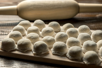 Uzbek national food Chuchvara, like dumplings, on a wooden board, in flour