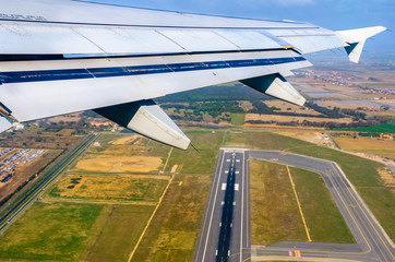 Looking through window aircraft at wing of airplane flying  over the  fiumicino where is situated...