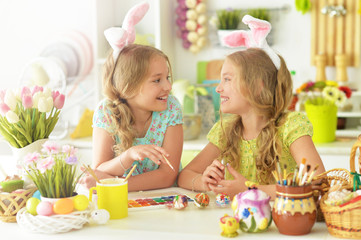Obraz na płótnie Canvas Cute twins wearing rabbit ears decorating Easter eggs