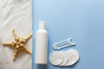 Fototapeta na wymiar flat lay composition with Bath skincare products. milk, cotton pads, sea star . blue spa background. top view