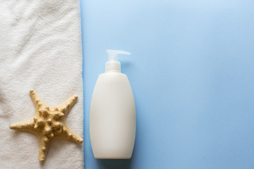 Obraz na płótnie Canvas white bottle, sea star and towel on blue background. body skin care concept . copy space
