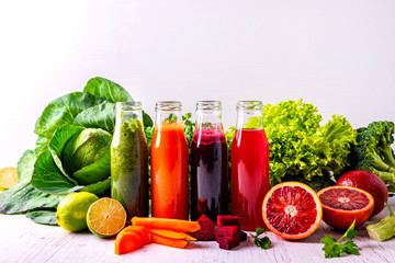 Different healthy vegan drinks with fruits and vegetables on the white wooden background.