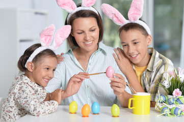 Portrait of family painting traditional Easter eggs in different colors at home