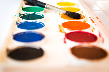 The palette of watercolor paint and one brush.Selective focus. Shallow DOF