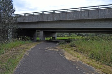 Fototapeta na wymiar Single lane road running underneath a bridge landscape
