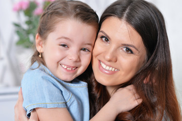 Close-up portrait of little girl with mother hugging