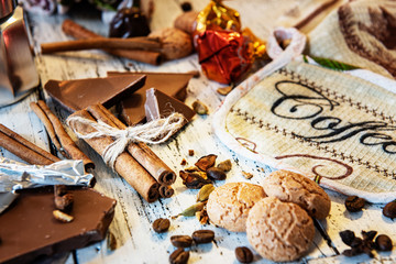 Cinammon sticks tied with jute rope, coffee pot, sweets and cookies on a white wooden background. Coffee break or breakfast backdrop.