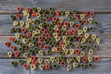 on a wooden background, heart-shaped pasta scattered across the background