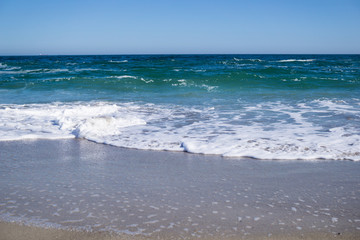 Sea waves on the beach, bright blue water